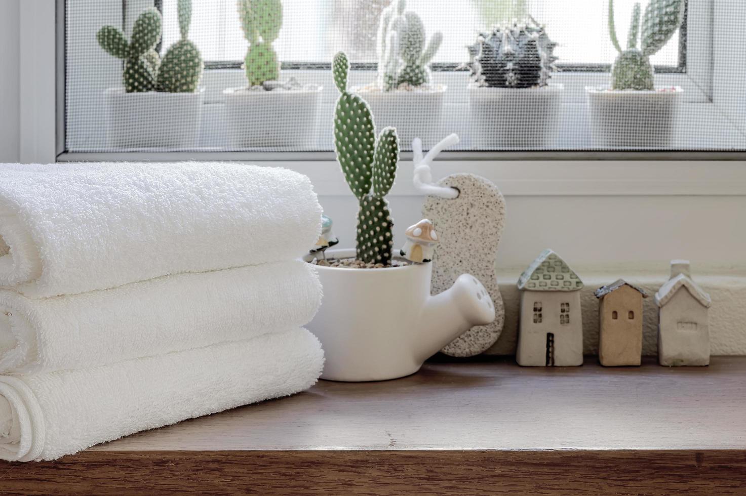 Folded clean towels with houseplant on wooden counter photo