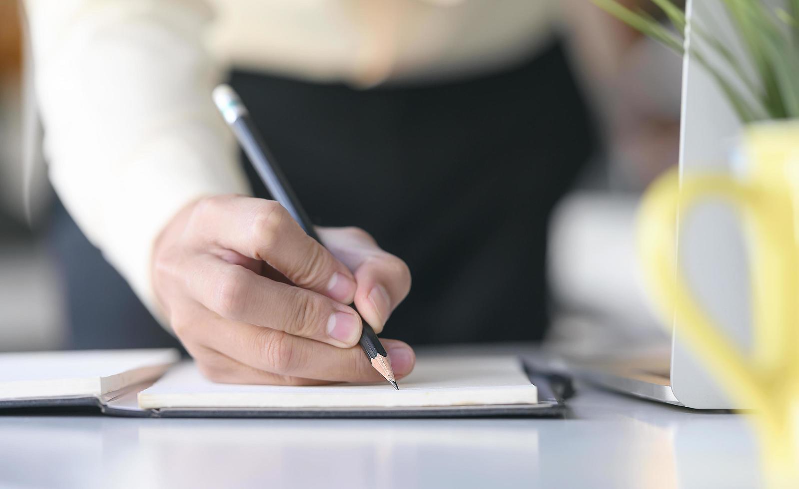 A hand writing on notebook with pencil photo