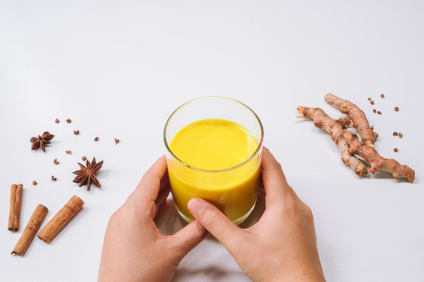 manos sosteniendo leche dorada cúrcuma latte foto