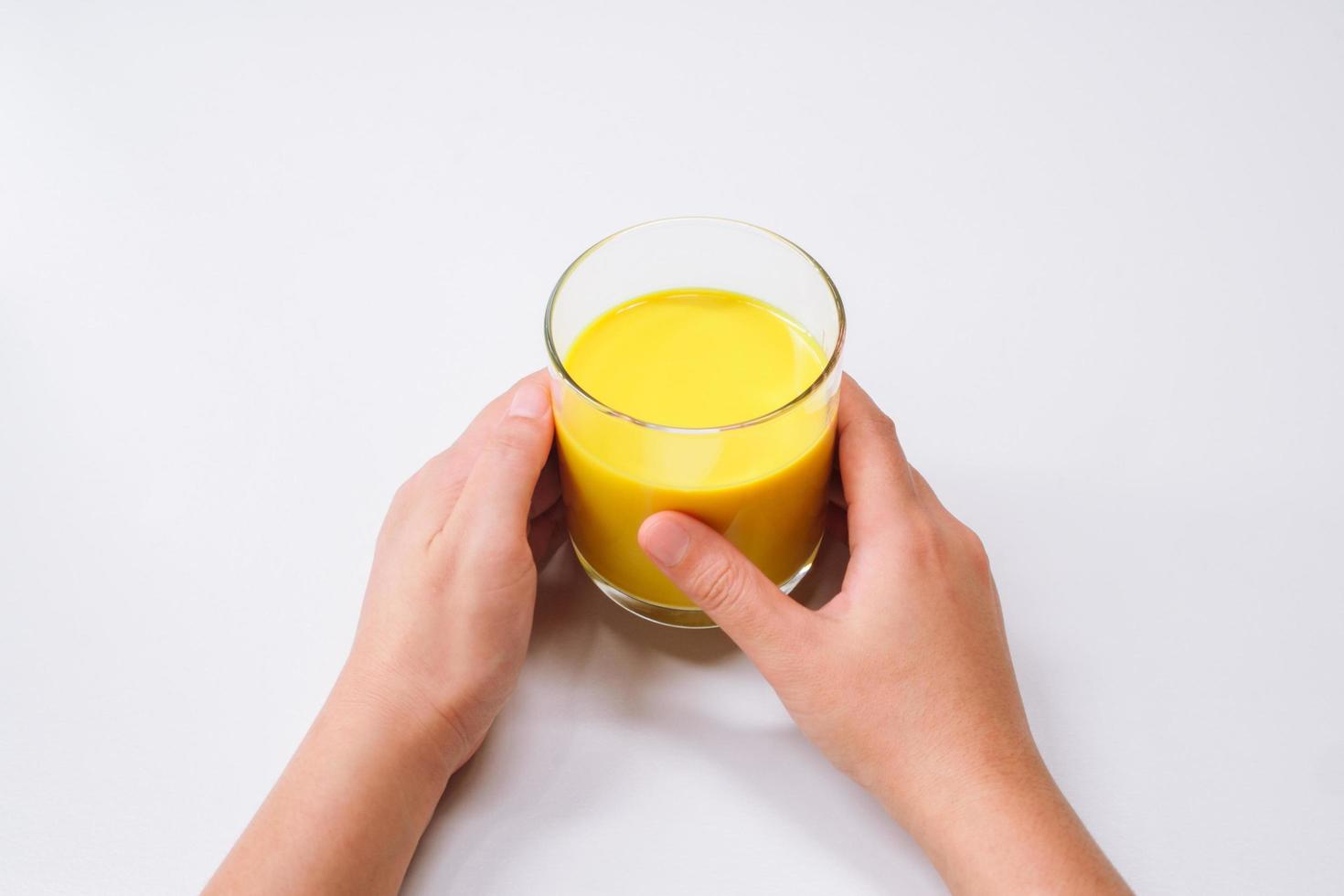 manos sosteniendo un vaso de leche dorada cúrcuma latte foto