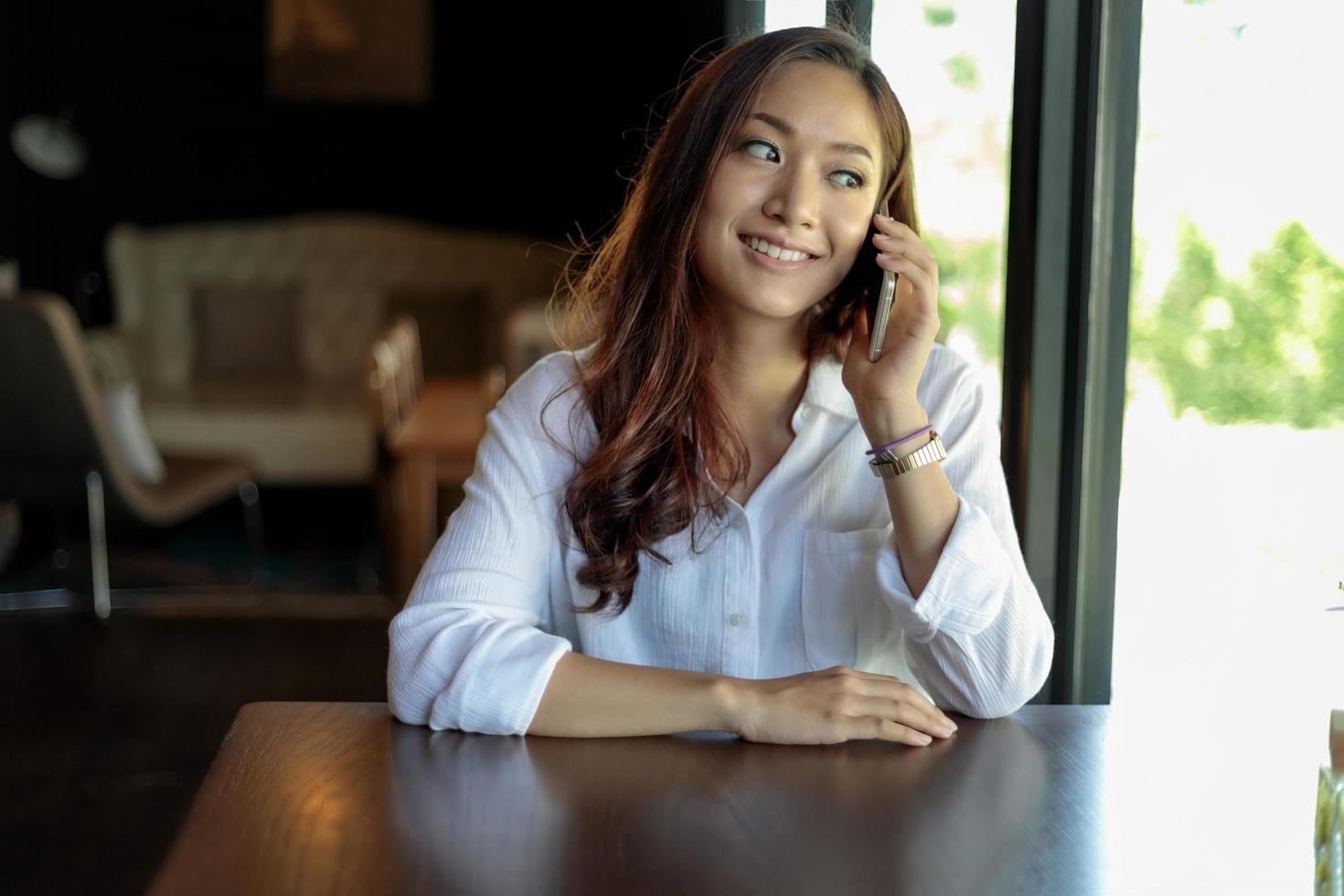 joven mujer asiática en la cafetería en el teléfono foto