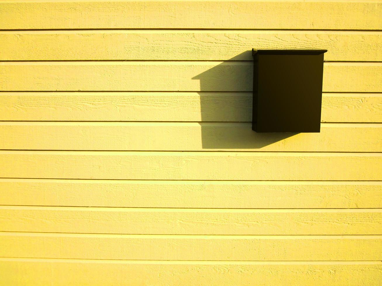 buzón marrón oscuro en la pared de madera de color amarillo brillante foto