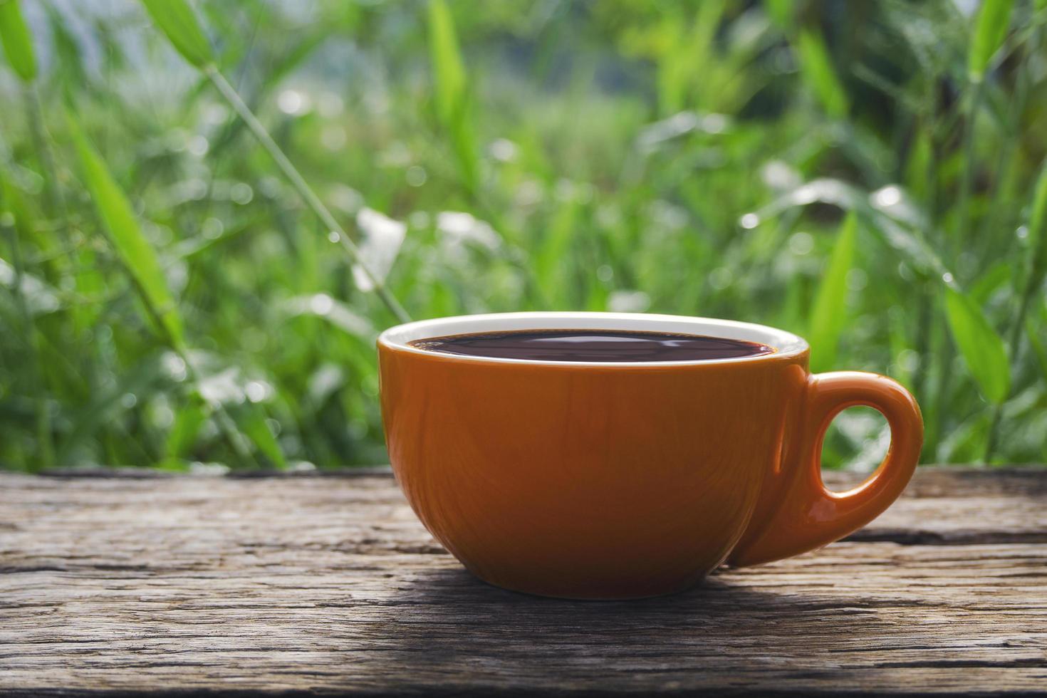 Orange cup of coffee on table outside photo