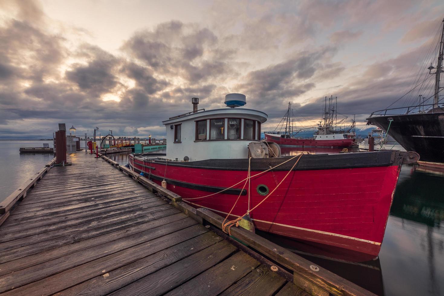 Red and white boat on dock under cloudy sky photo