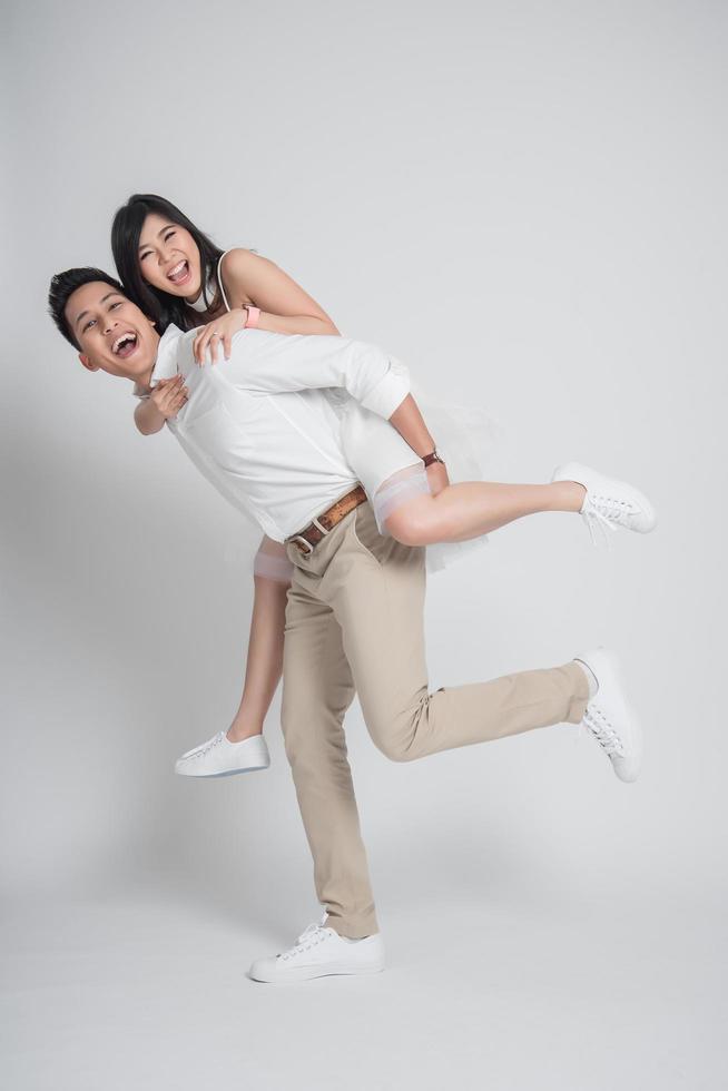 Happy groom gives a bride piggyback ride photo