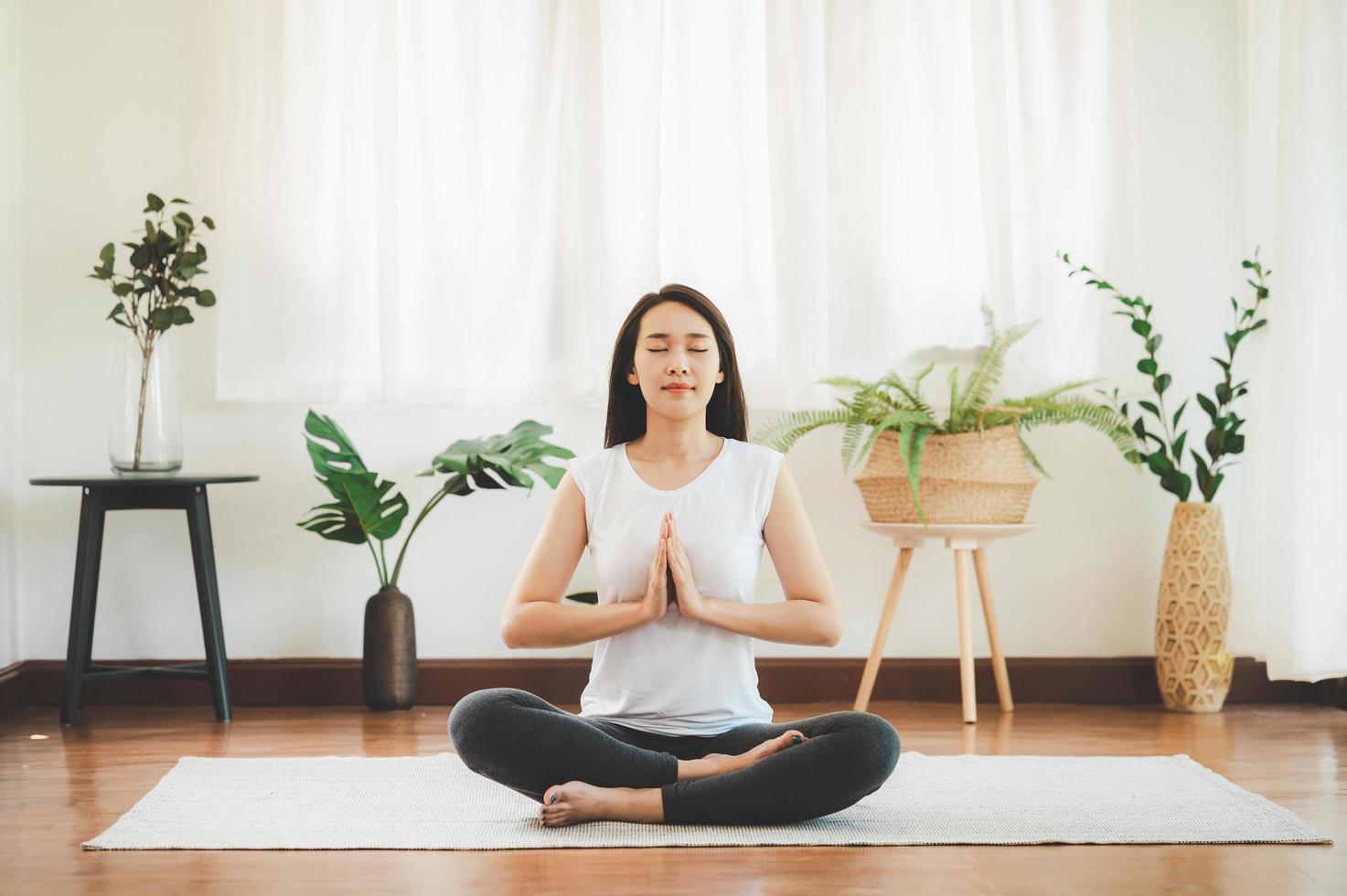 Mujer asiática haciendo yoga meditación en casa foto