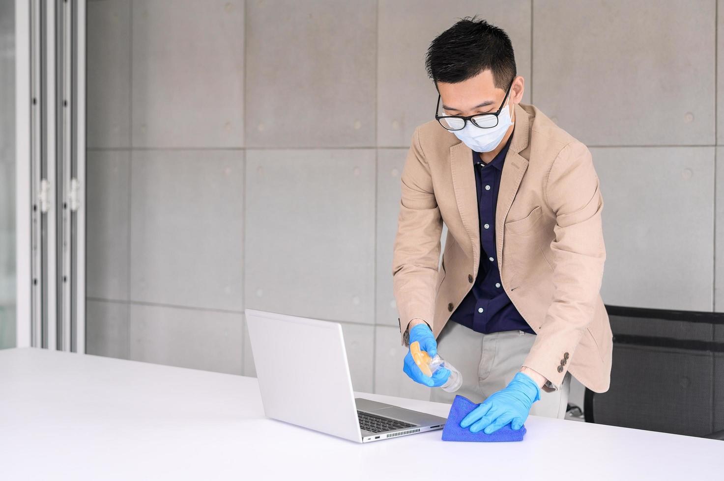 Businessman using microfiber cloth to clean laptop and table photo