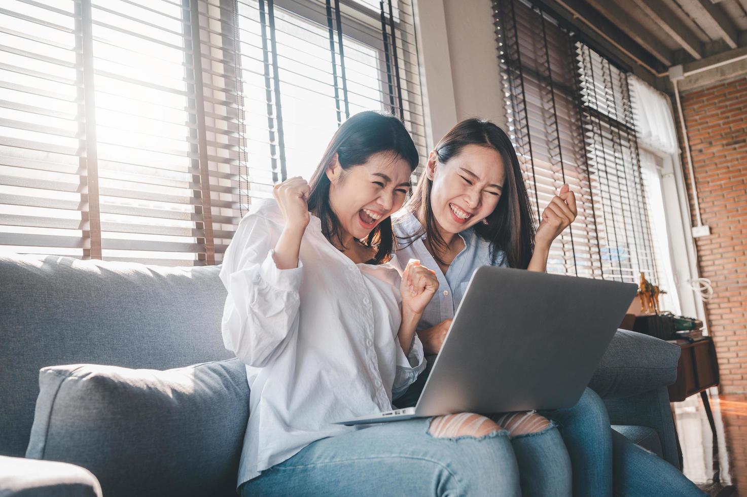 Asian women best friends excited while using laptop at home photo