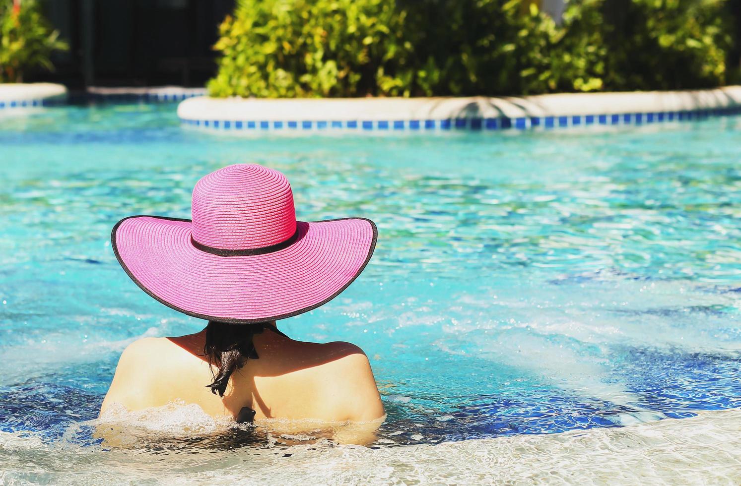 mujer con sombrero rosa relajante en la piscina foto