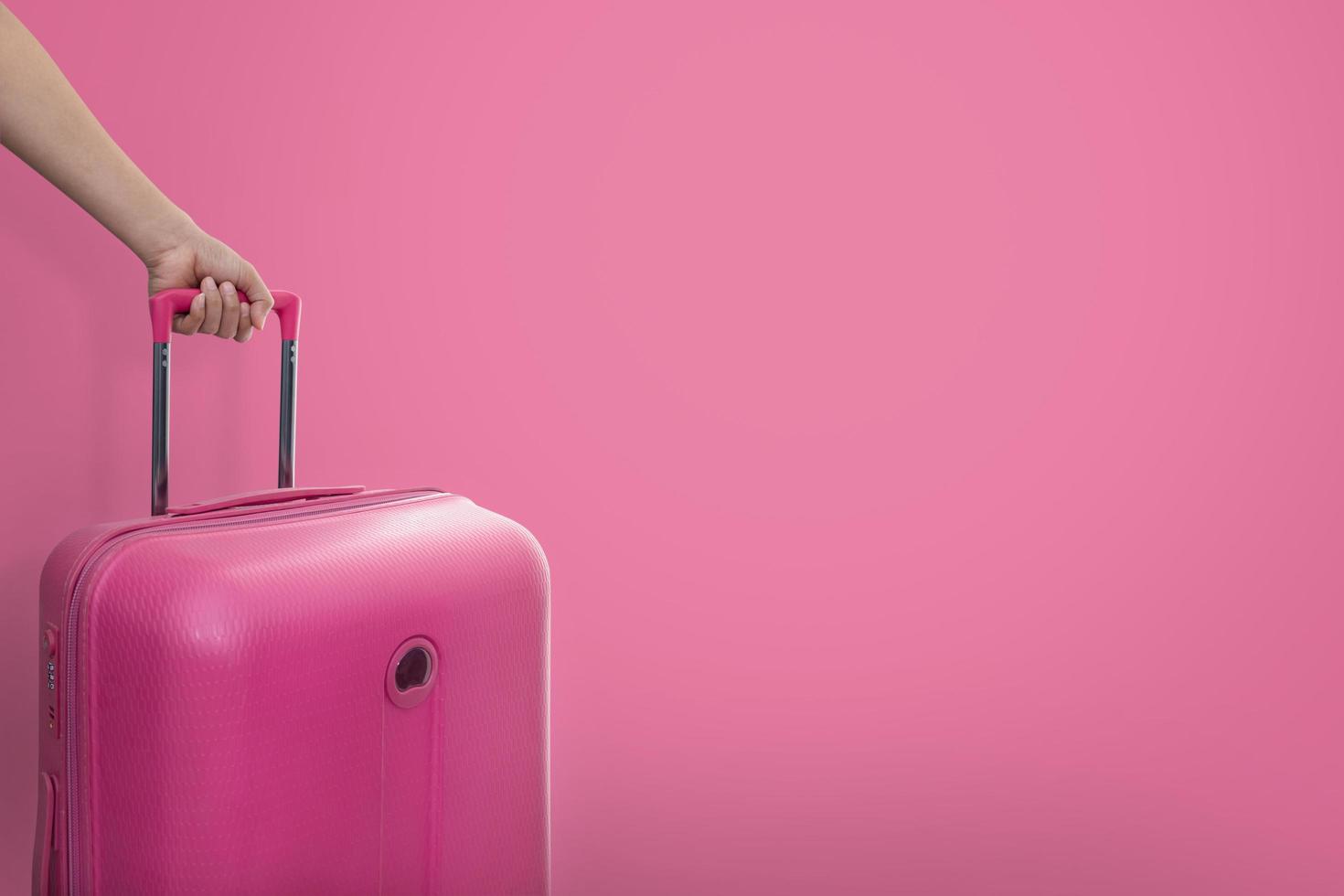 Hand holding pink suitcase photo