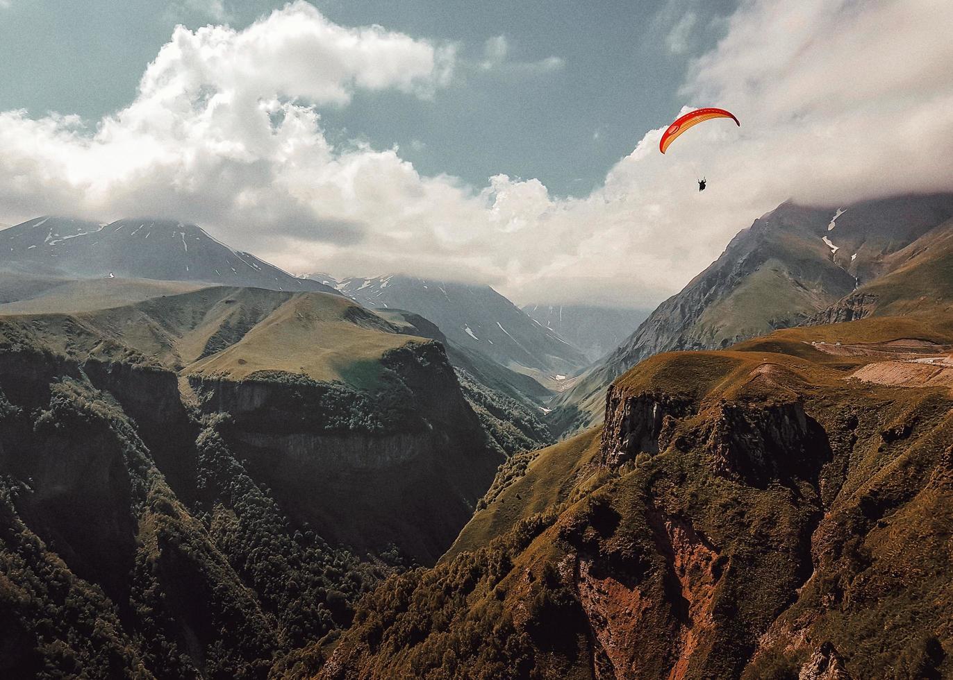 Person paragliding over mountains photo