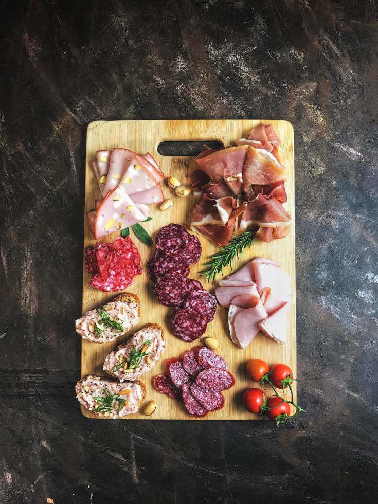 carnes en rodajas sobre tabla de cortar de madera foto