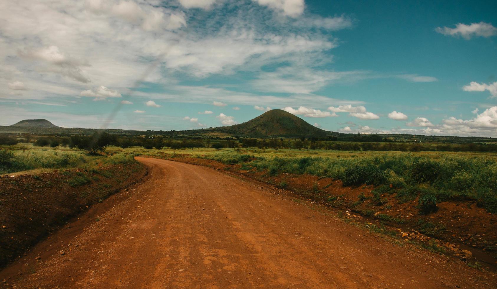 Dirt road across hill under cloudy sky photo