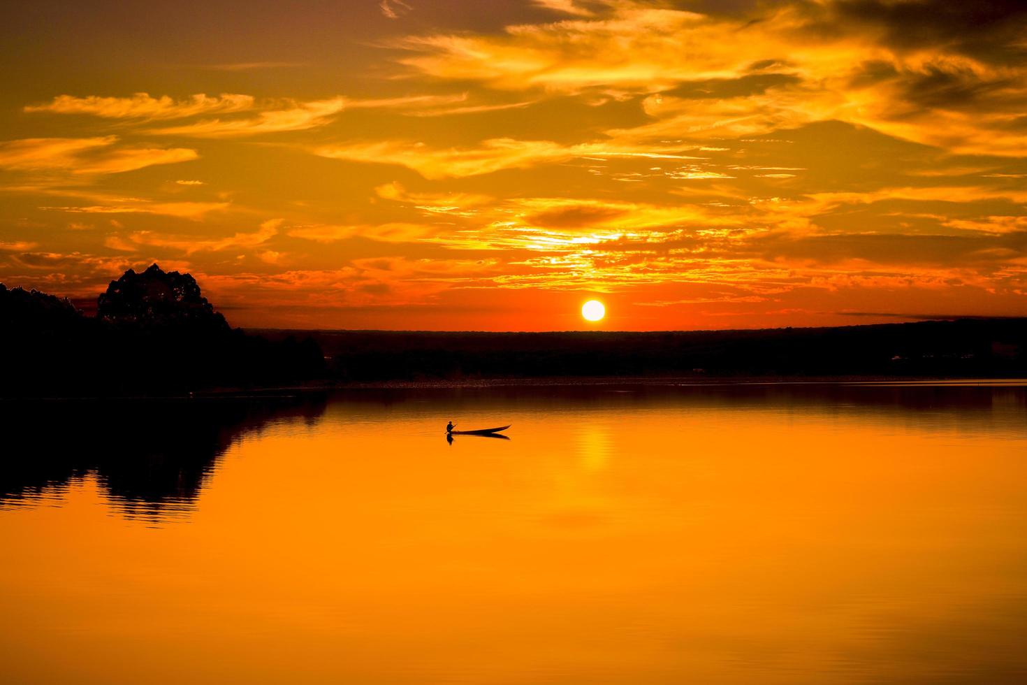 Man and boat on water at sunset photo