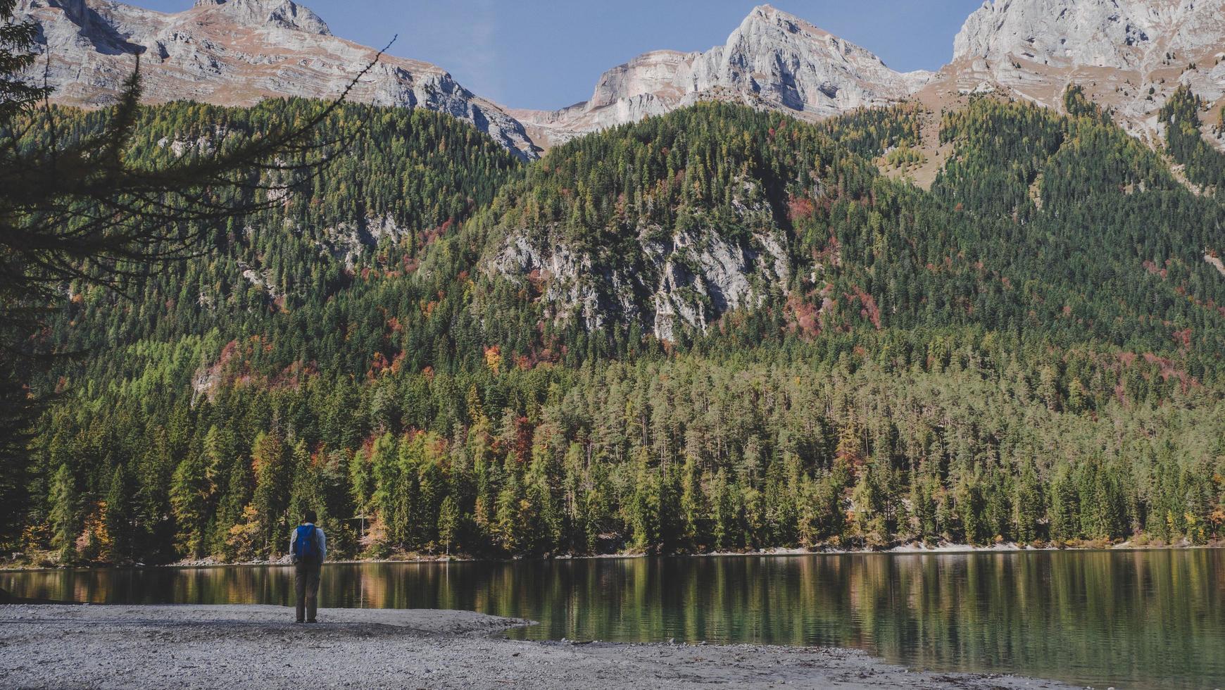 Person standing in front of water and mountains photo