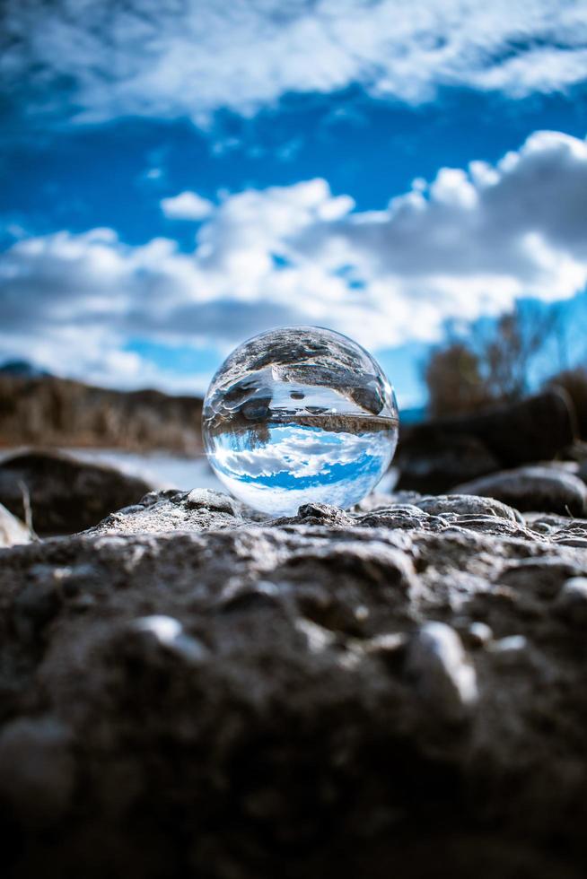 Glass ball on rocks with blue sky photo