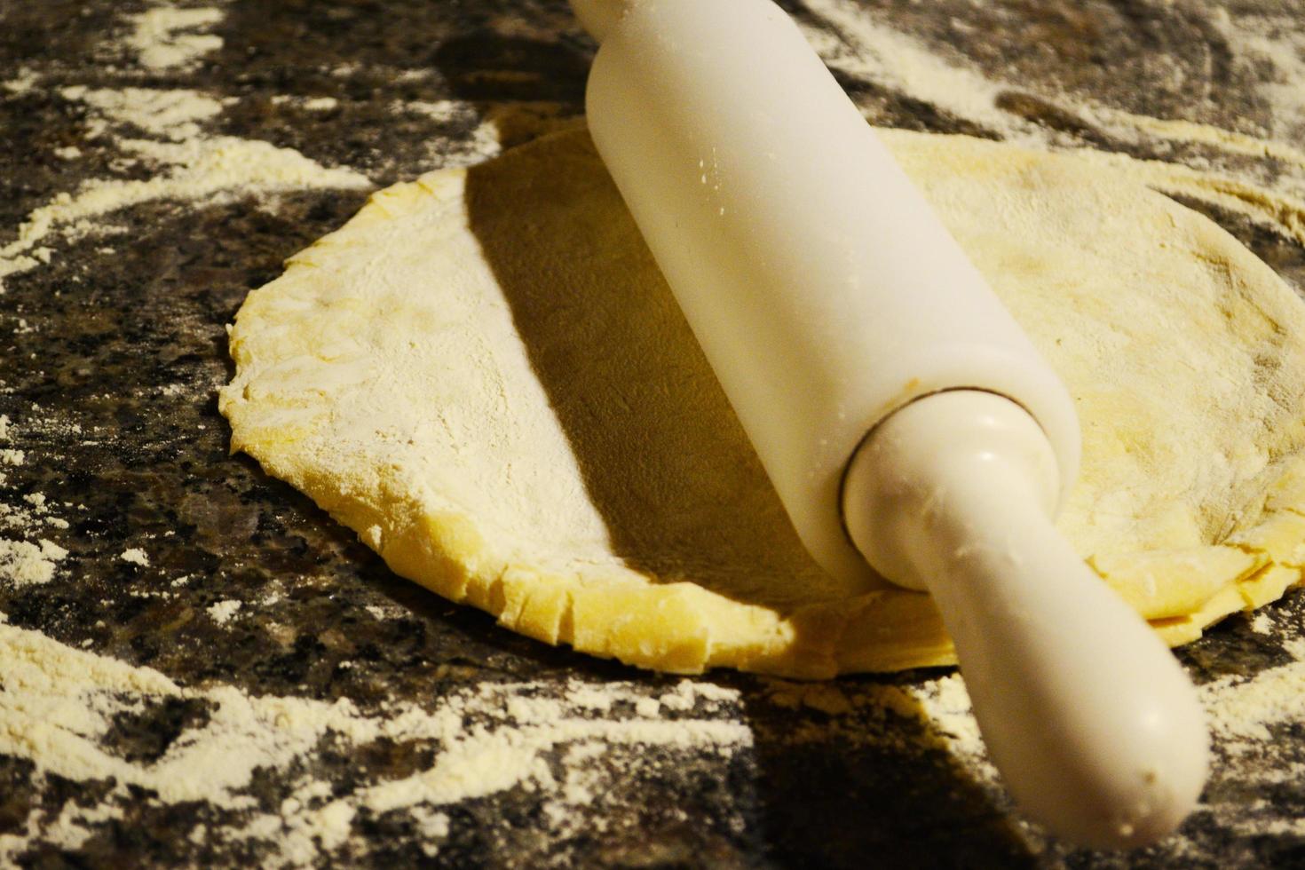 White rolling pin on dough photo