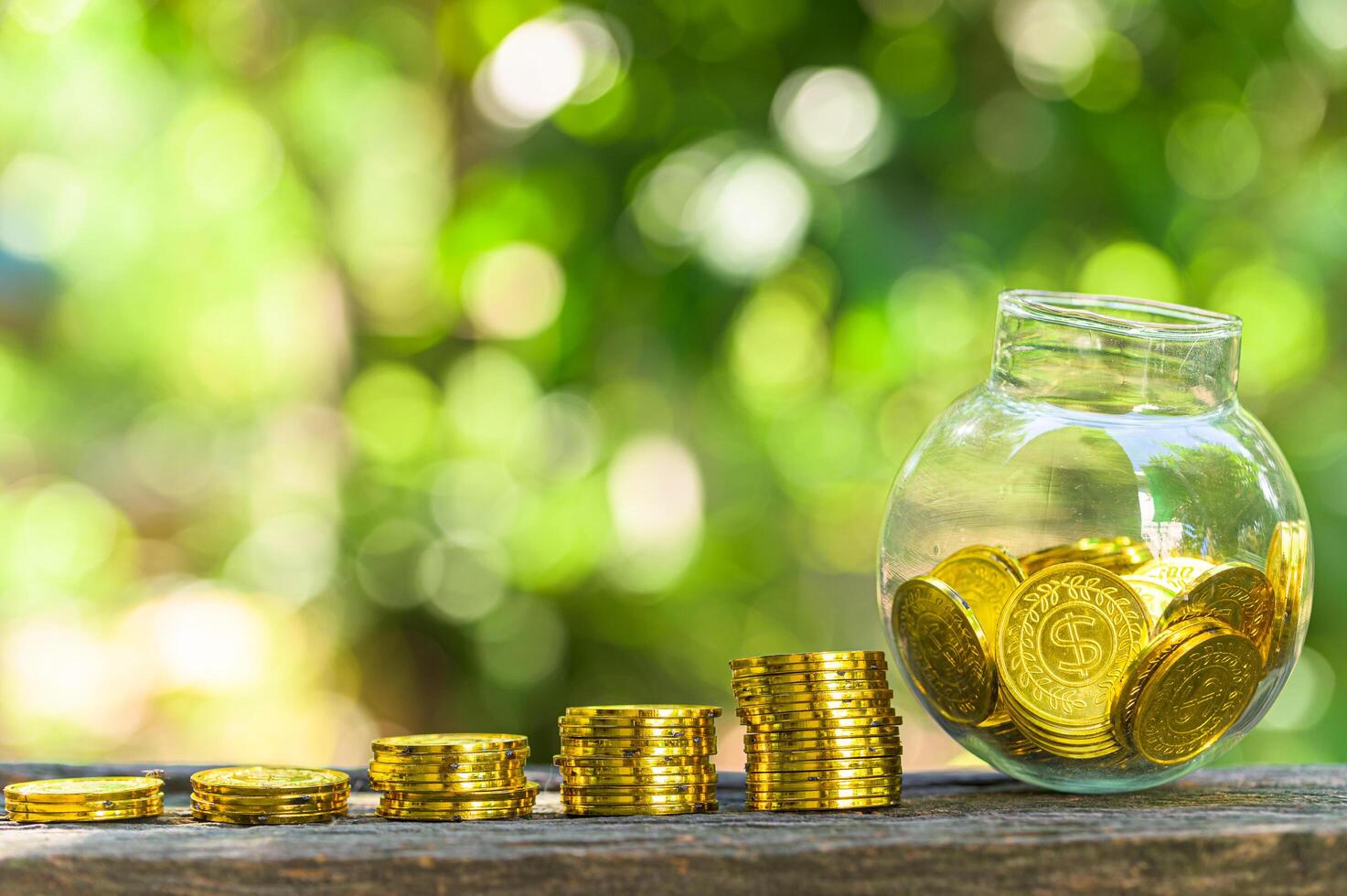 Stack of gold coins and jar on table outside photo