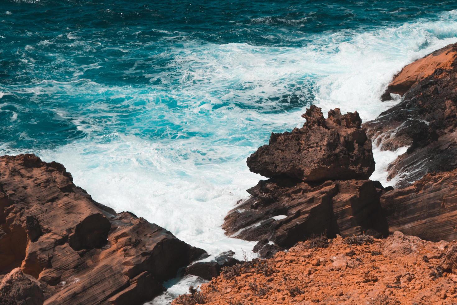 Waves crashing into rocky seashore photo