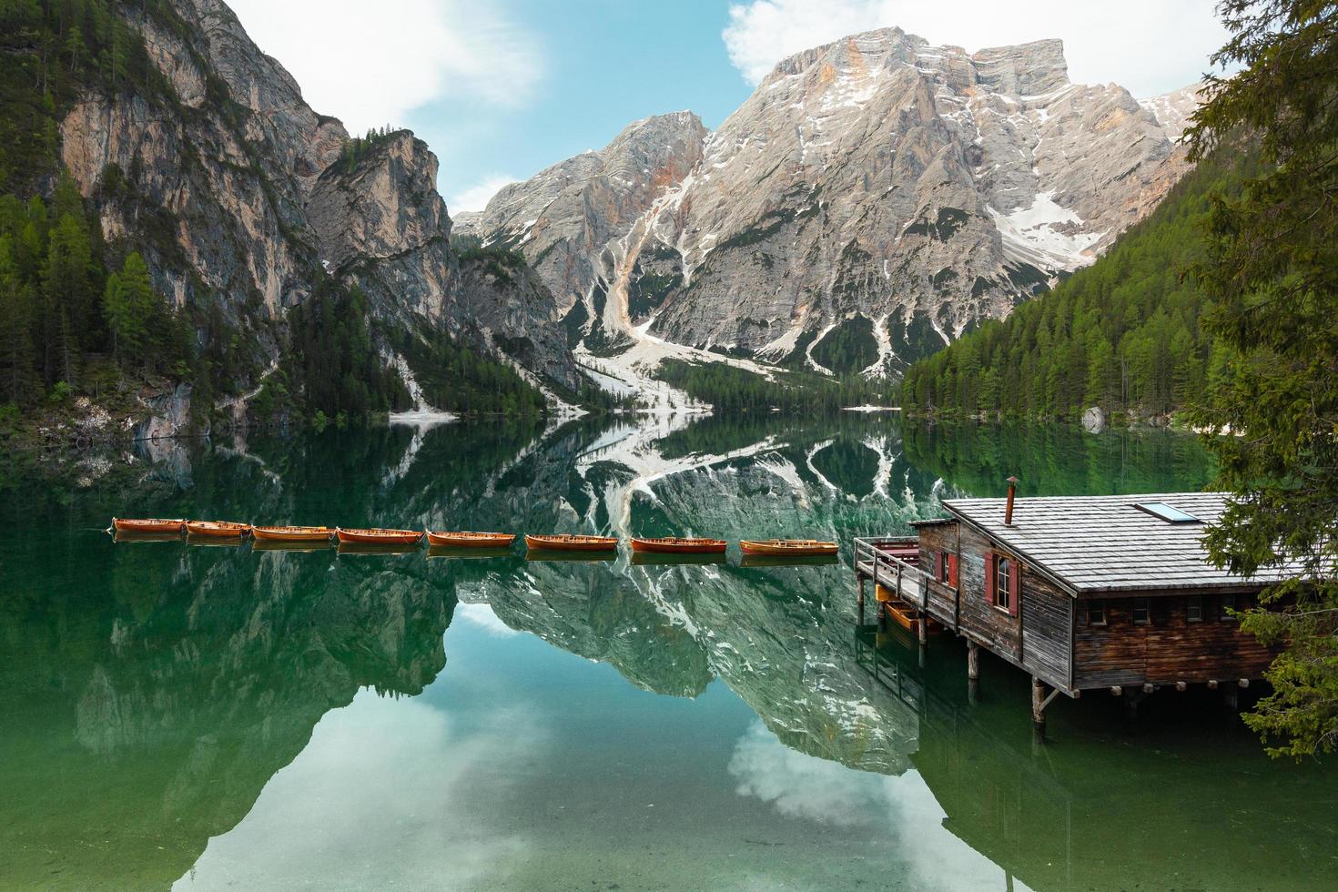 Lakehouse, dock, and boats beside mountain photo