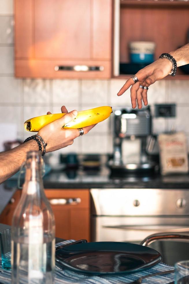 Hand passing banana to another hand photo