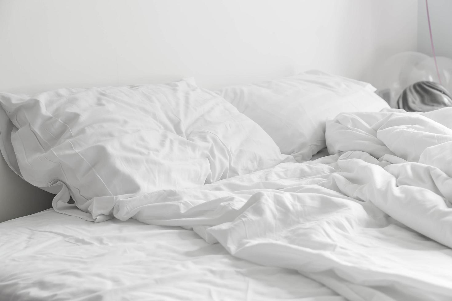 Cama arrugada con decoración de almohada desordenada blanca en el dormitorio foto