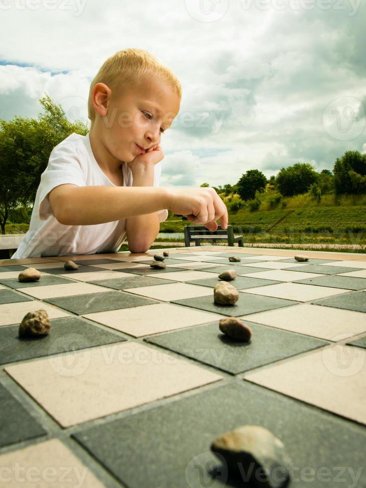 Child playing draughts or checkers board game outdoor photo