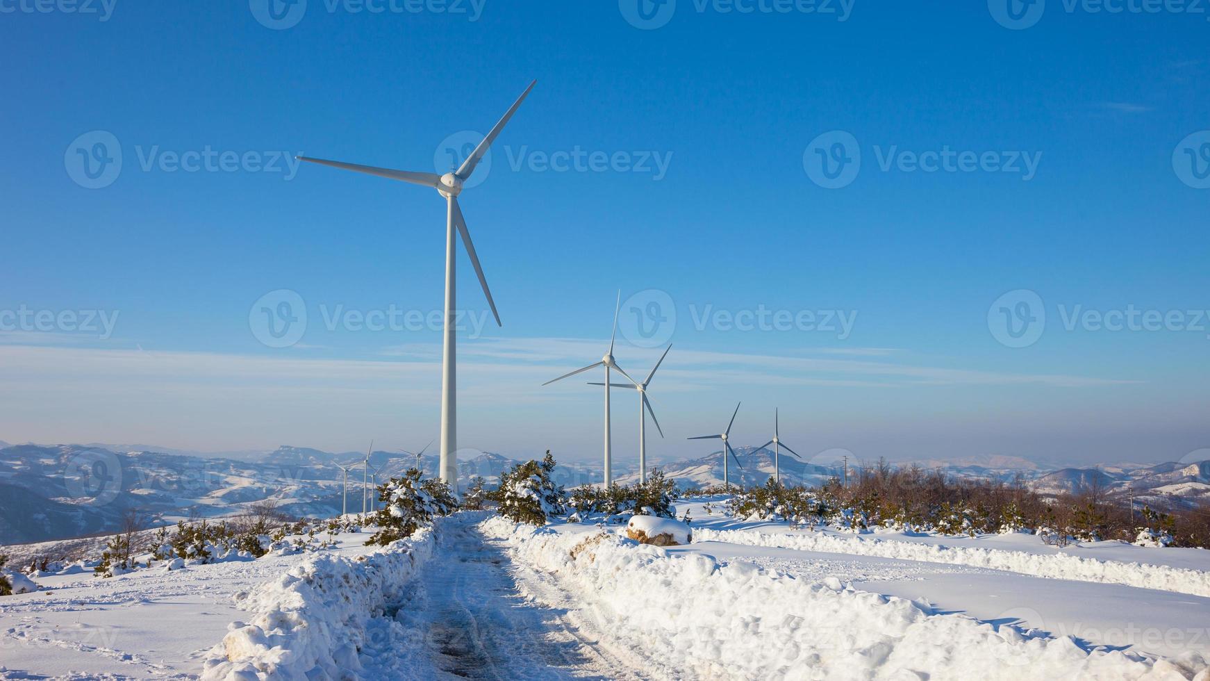 Typical windmill or aerogenerator of aeolian energy on snowy lan photo