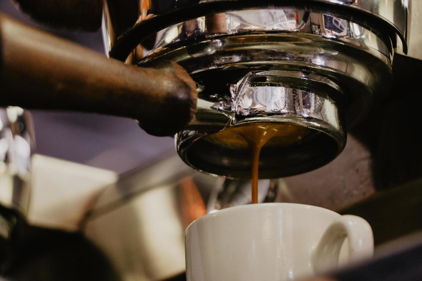 taza de cerámica blanca debajo de la cafetera espresso foto