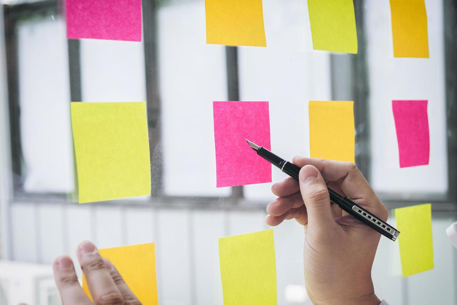 Young creative professional using notes on glass wall  photo