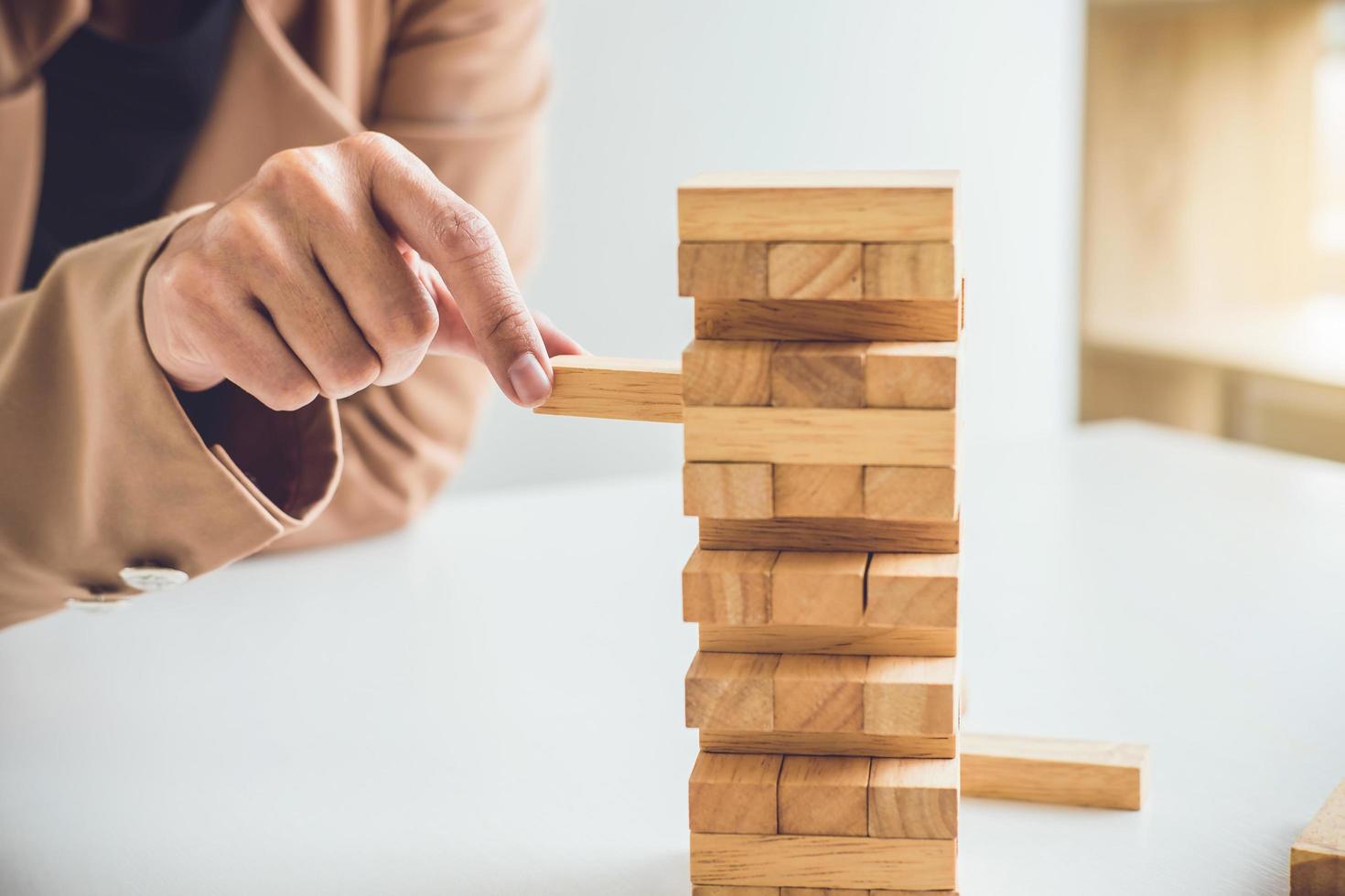 Joven empresaria colocando un bloque de madera en la torre foto