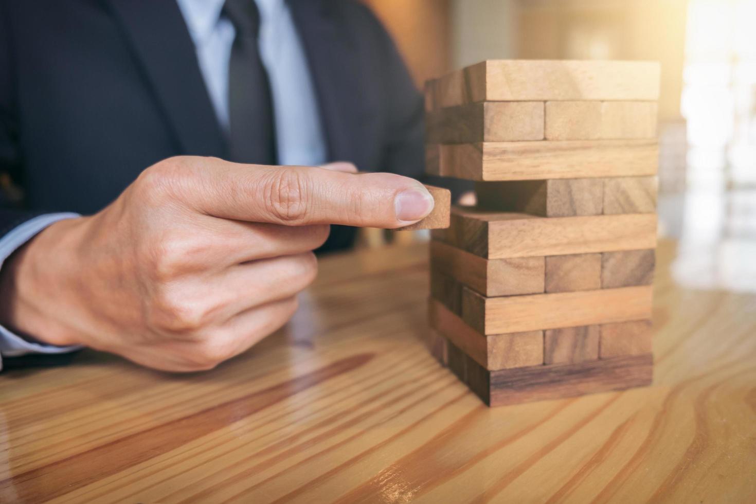 Empresario colocando y tirando de un bloque de madera en la torre. foto