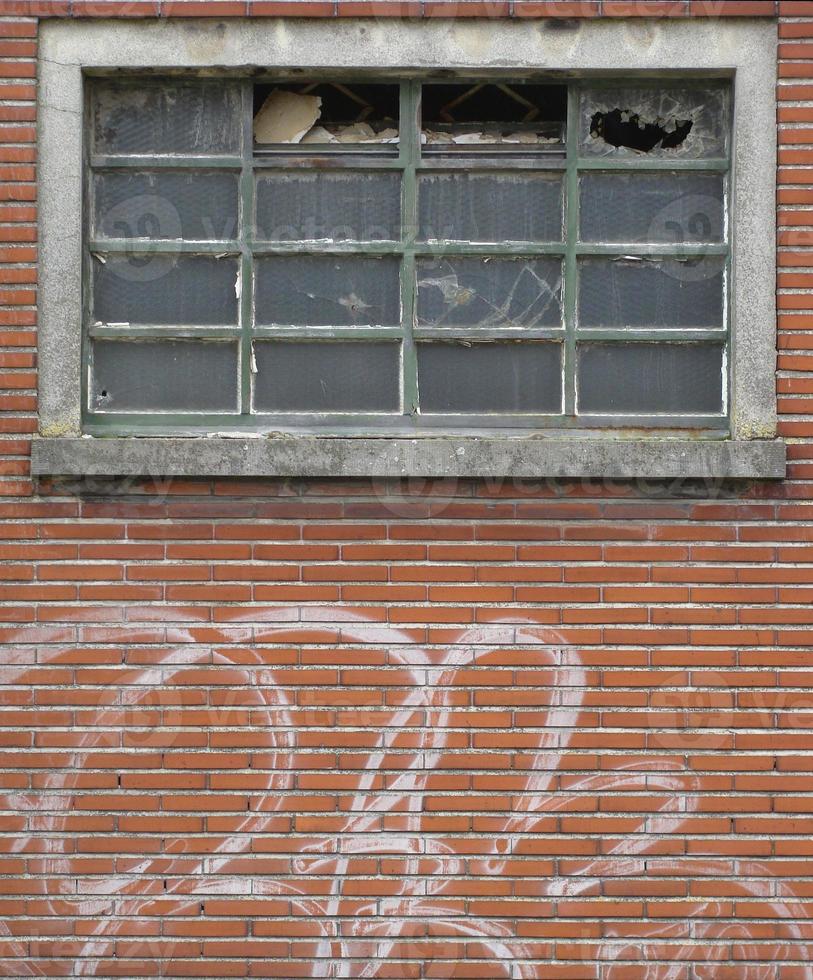 Fachada de edificio abandonado con ventanas rotas y graffiti foto