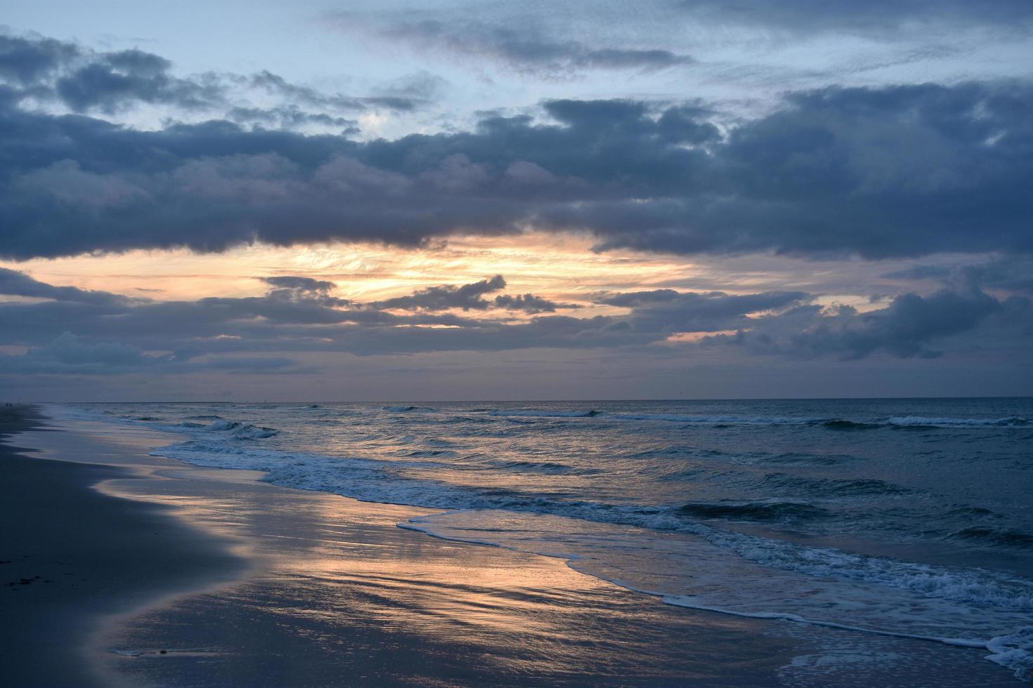 Waves crashing on shore during sunset photo