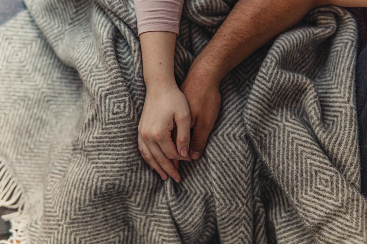 People holding hands on top of blanket photo