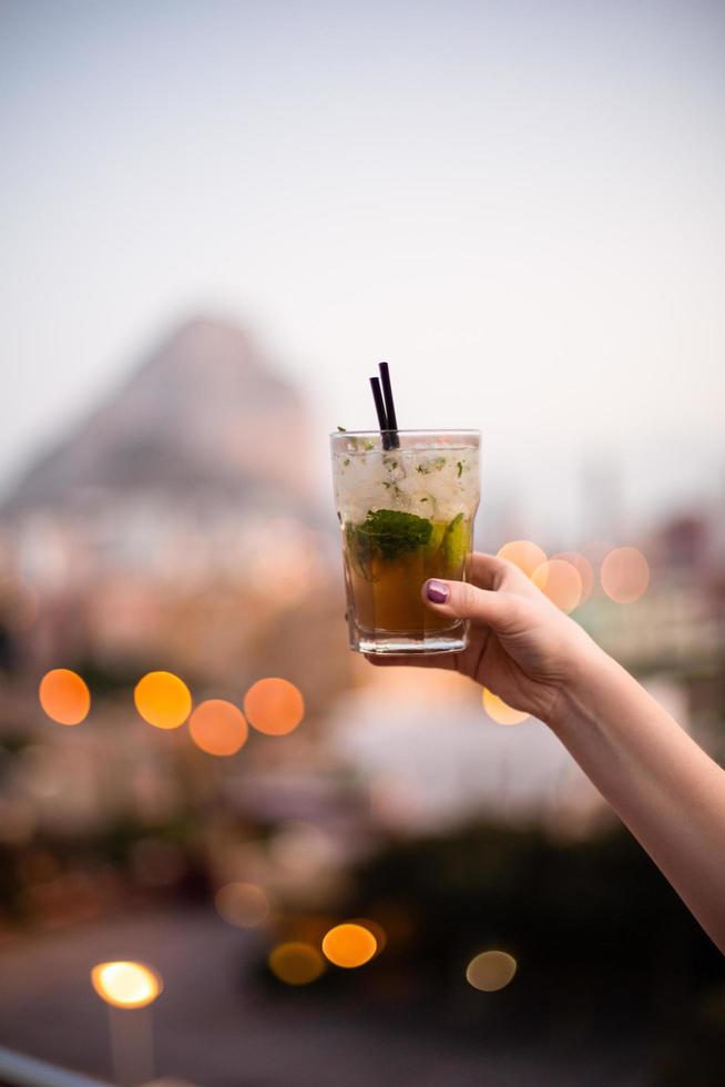 Person holding mixed drink with city in background photo