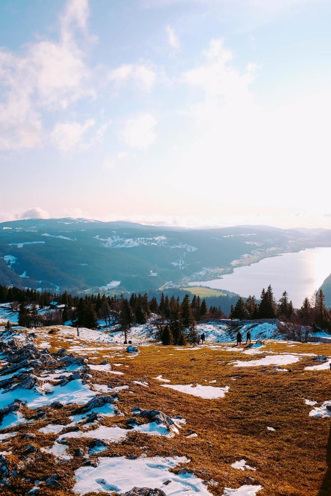 Grass, snow, trees, and body of water photo