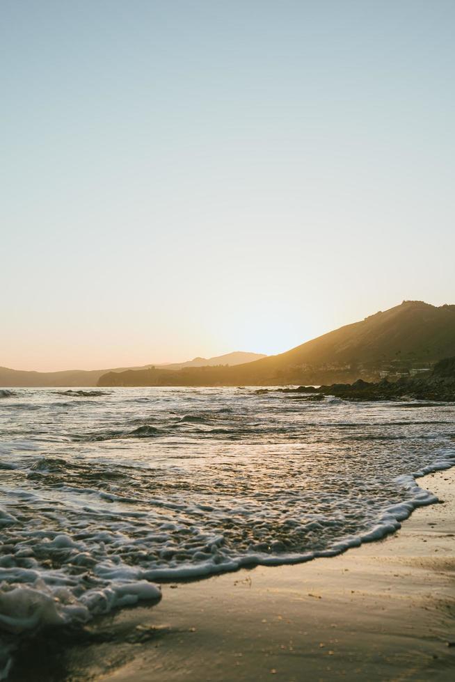 orilla del mar y montaña durante la puesta de sol foto