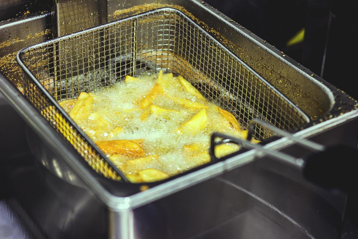 Sliced potatoes in deep fryer photo