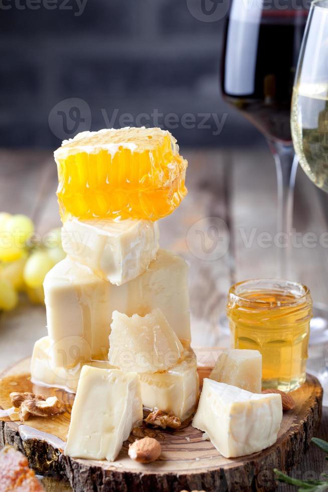 uva, queso, higos y miel con unas copas de vino. foto