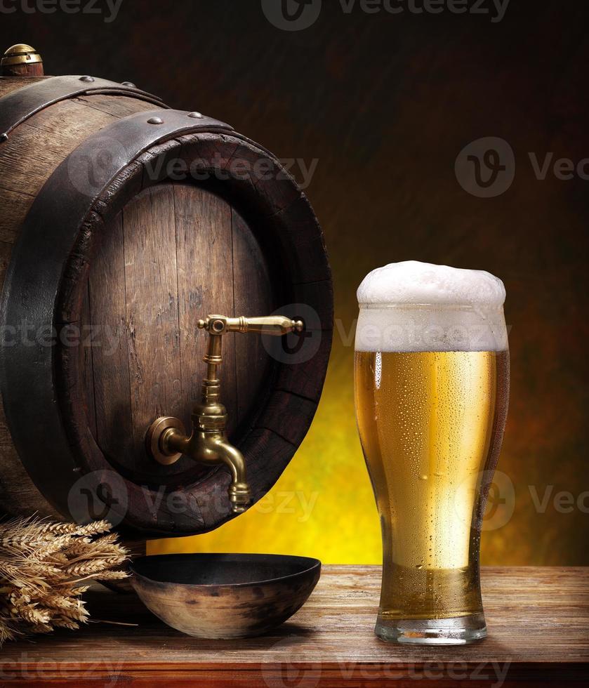 Beer barrel with a glass pint of beer on wood table photo