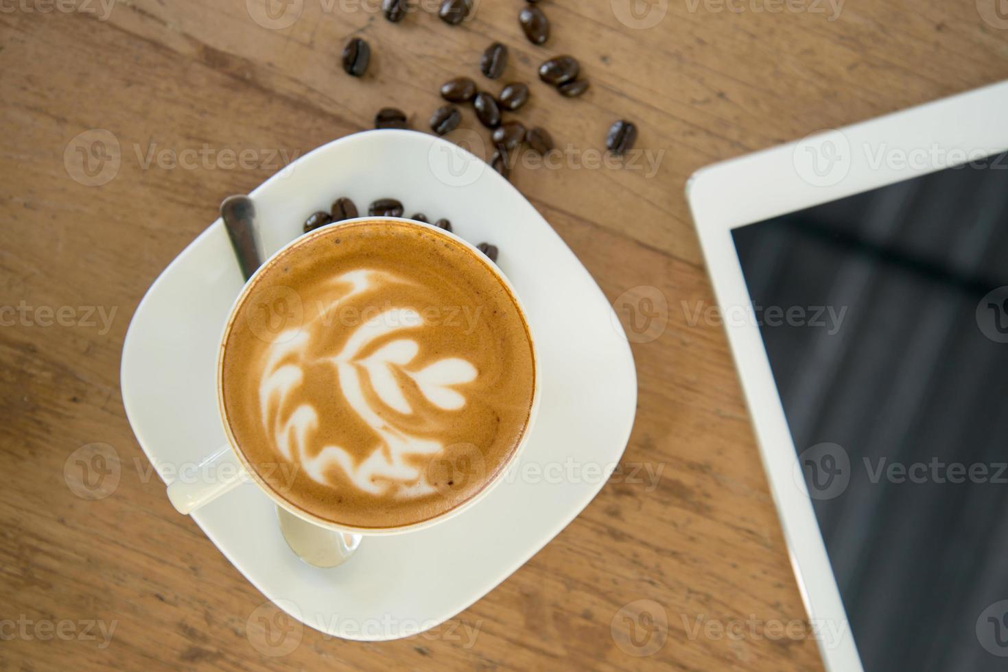 Taza de café en la mesa de café con tableta foto