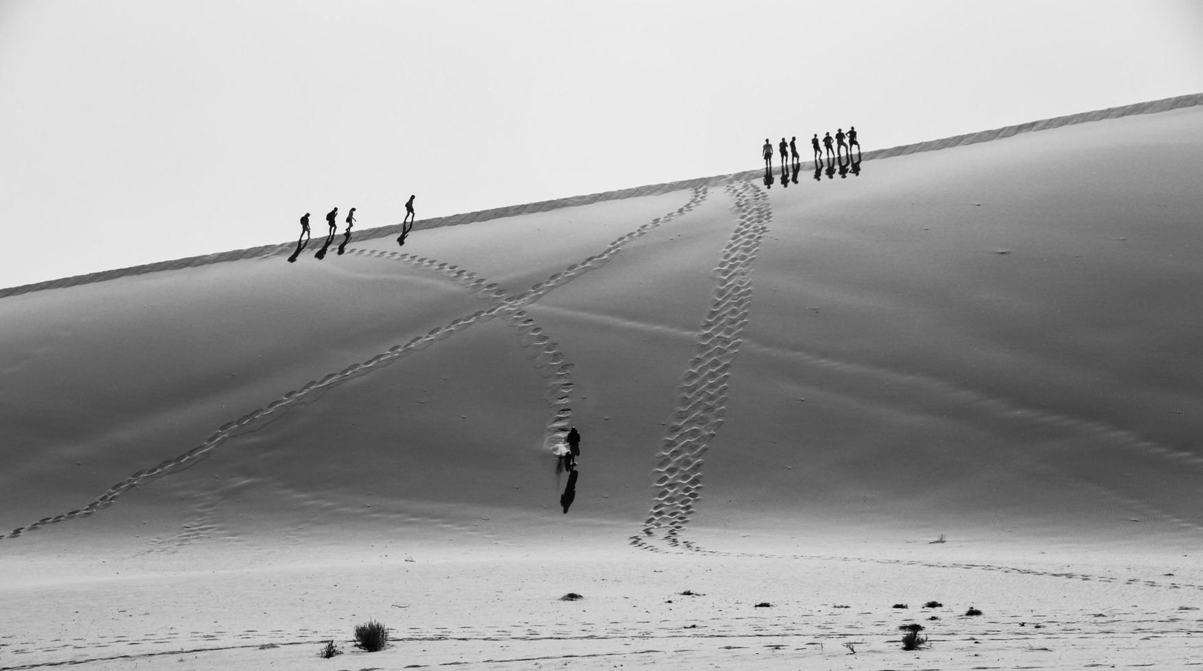 Grayscale photo of people walking on desert