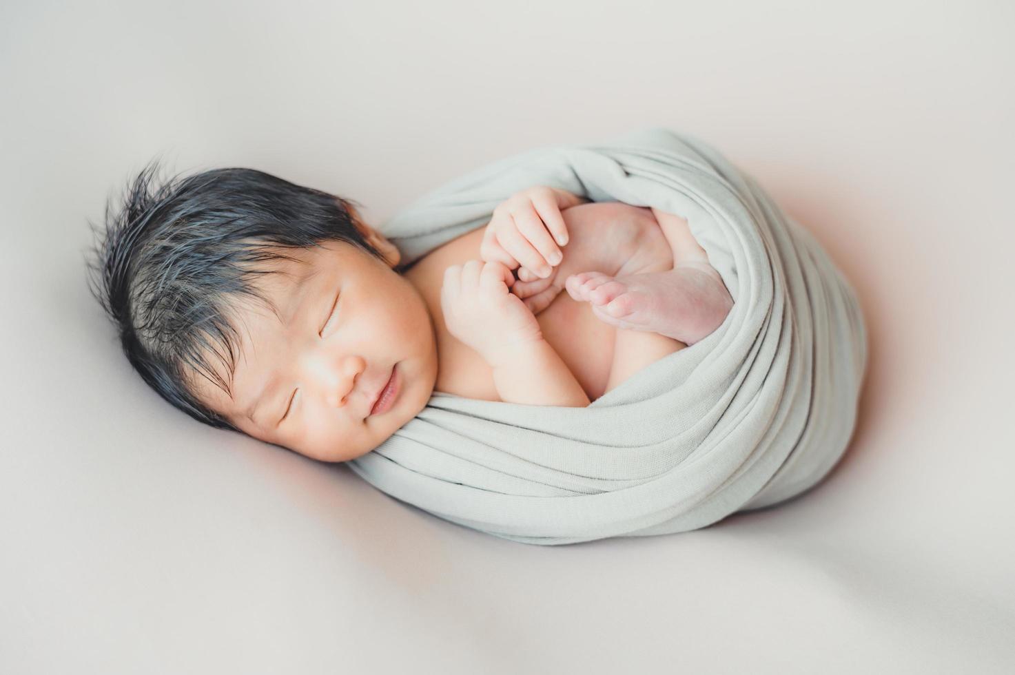 bebé recién nacido asiático wrapprd en capullo durmiendo foto