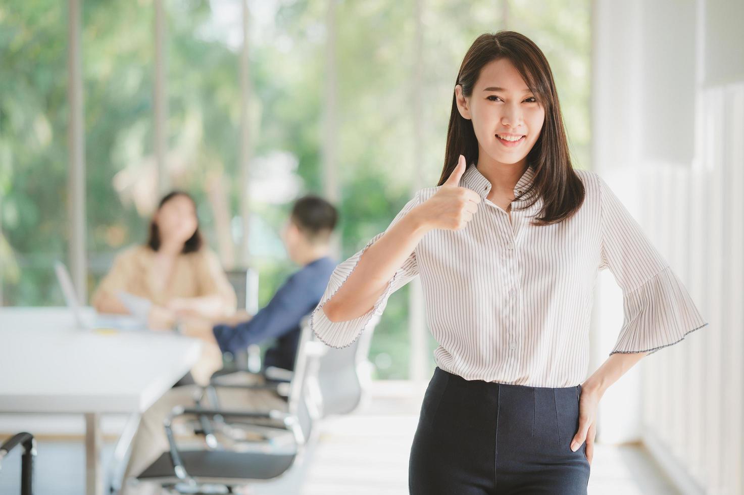 La empresaria asiática sonriendo con los pulgares para arriba gesto foto