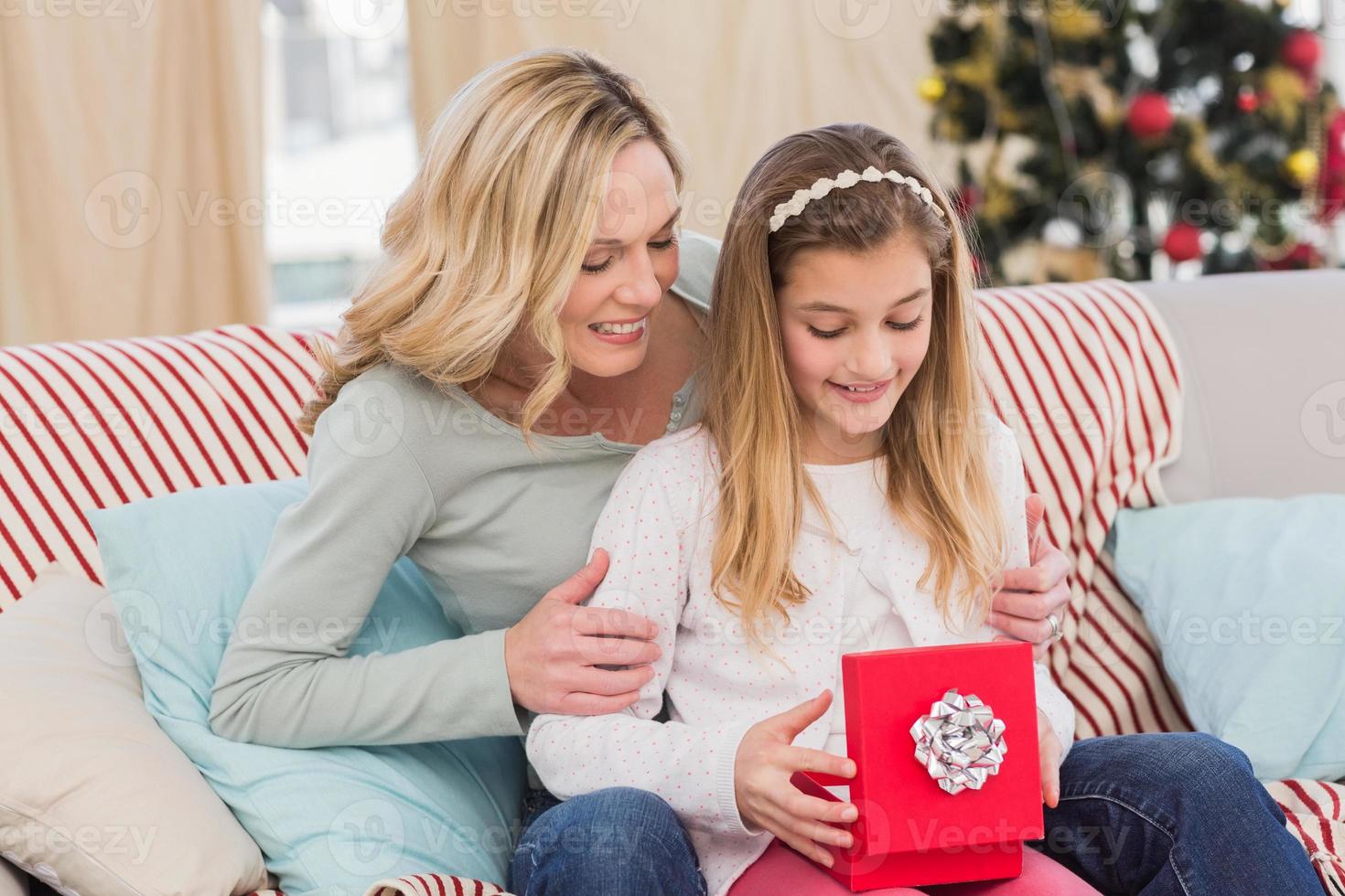 Daughter opening christmas gift with mother photo