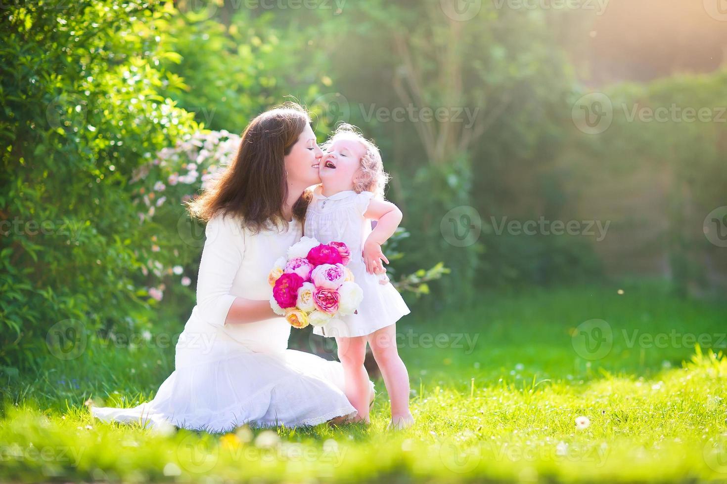 feliz madre y su pequeña hija con flores en el jardín foto