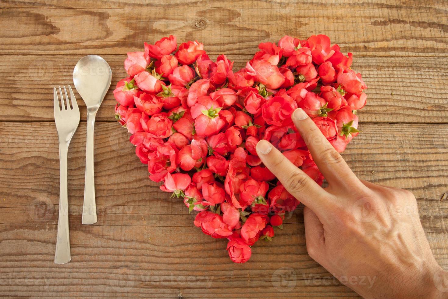 Corazón de rosas rojas sobre fondo de madera, en el almuerzo foto