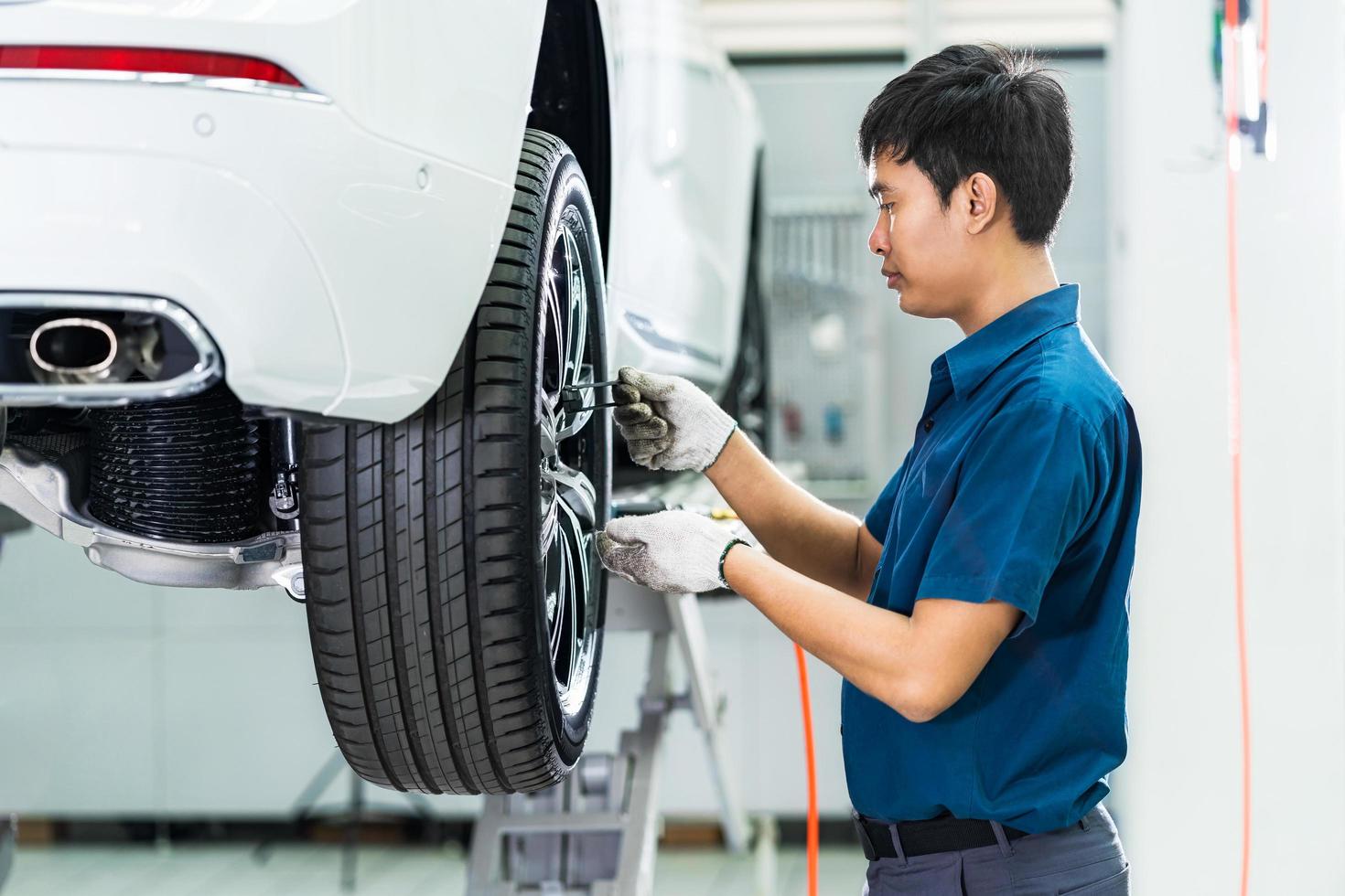 Asian mechanic checking car wheels photo