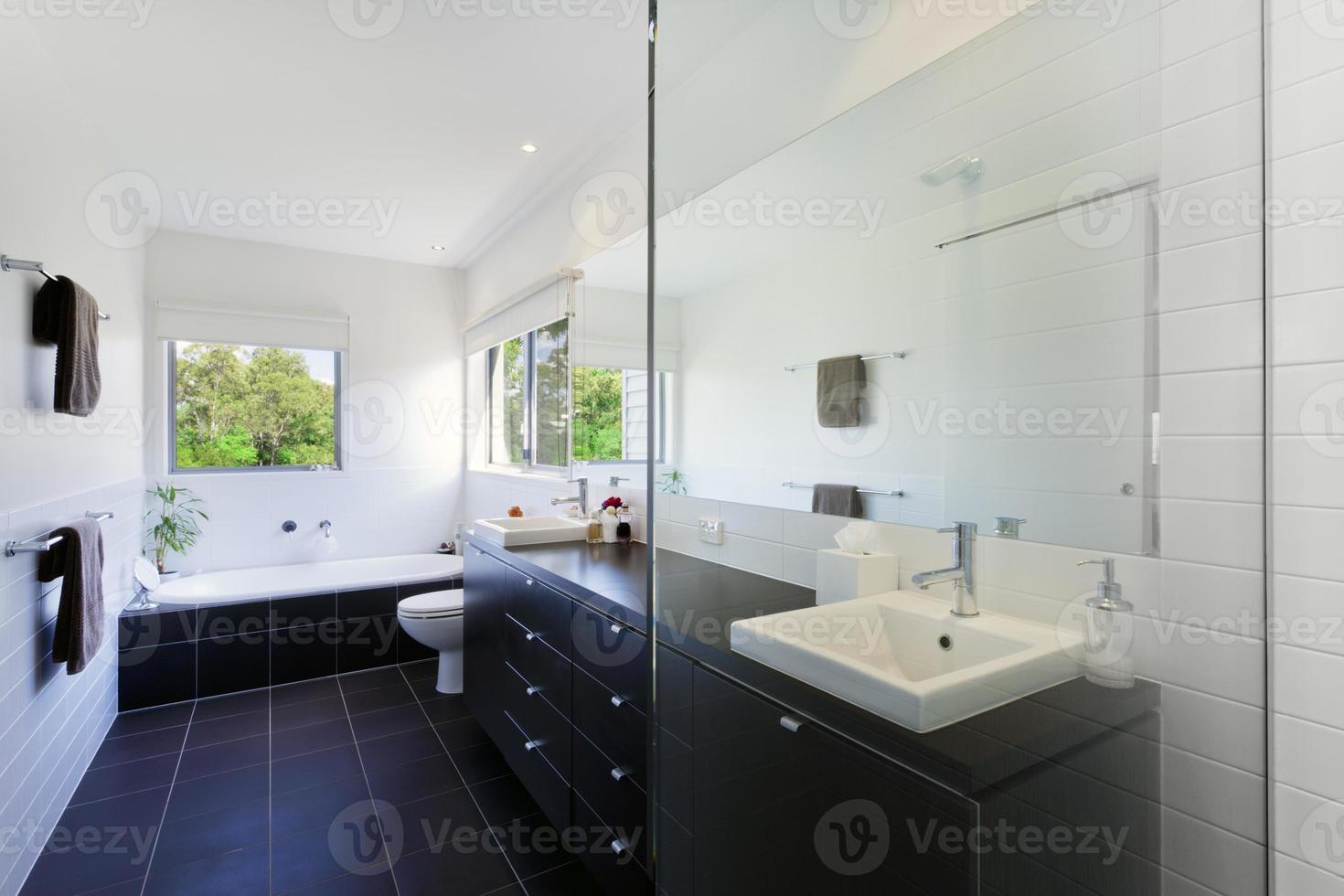un baño limpio y moderno con azulejos oscuros y paredes blancas foto
